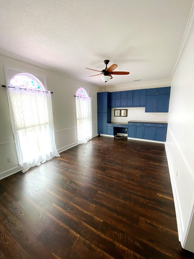 unfurnished living room featuring dark wood-type flooring, ornamental molding, a textured ceiling, and blue cabinets