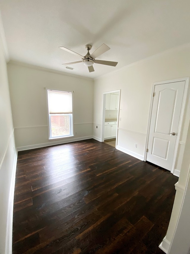 spare room featuring dark wood-type flooring, ornamental molding, and ceiling fan