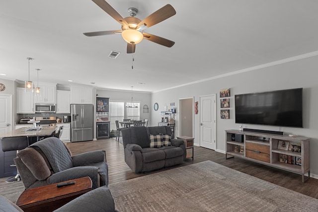 living room with ceiling fan with notable chandelier, dark hardwood / wood-style flooring, and ornamental molding