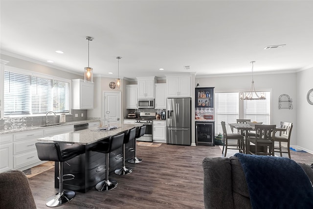 kitchen featuring appliances with stainless steel finishes, pendant lighting, a kitchen bar, and a kitchen island