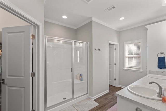 bathroom featuring hardwood / wood-style flooring, a shower with shower door, ornamental molding, and vanity