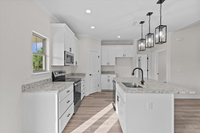 kitchen featuring stainless steel appliances, a sink, a kitchen island with sink, light wood-style flooring, and white cabinetry