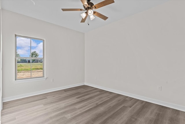 spare room featuring wood finished floors, baseboards, and ceiling fan
