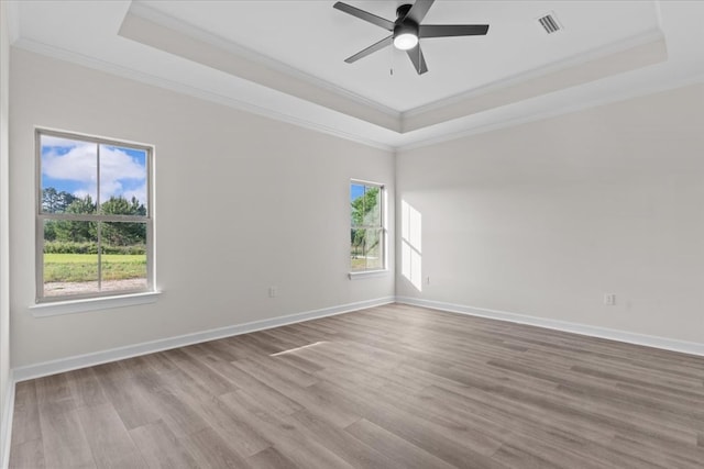 unfurnished room featuring a tray ceiling, baseboards, a ceiling fan, wood finished floors, and ornamental molding