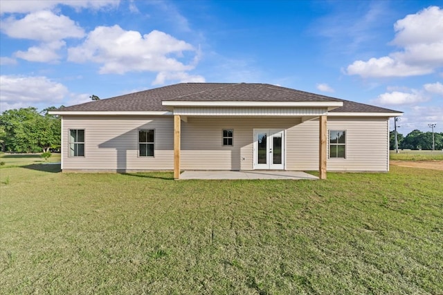 rear view of house with a yard, a patio area, a shingled roof, and french doors
