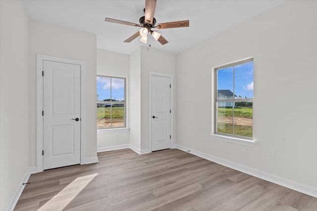 unfurnished bedroom featuring light wood-style flooring, a ceiling fan, and baseboards