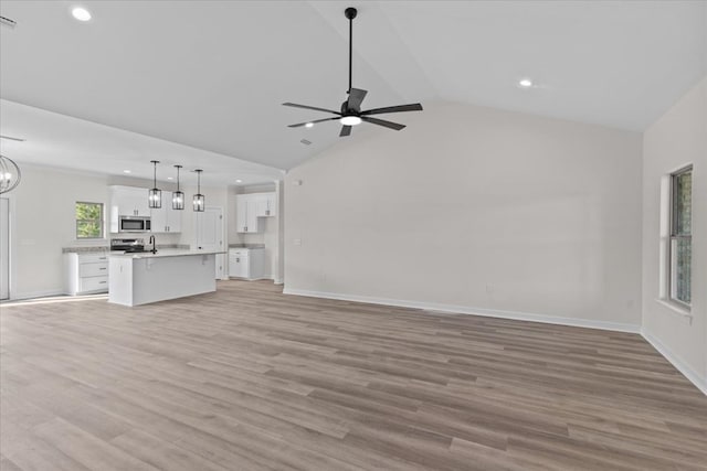 unfurnished living room with ceiling fan with notable chandelier, baseboards, and recessed lighting
