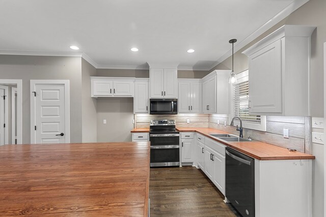 kitchen featuring sink, butcher block countertops, white cabinetry, decorative light fixtures, and appliances with stainless steel finishes