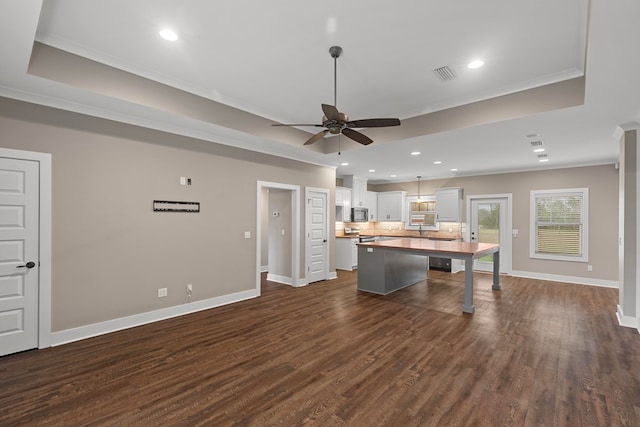 kitchen featuring a kitchen island, dark hardwood / wood-style floors, a breakfast bar area, white cabinets, and a tray ceiling