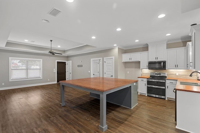 kitchen with range with two ovens, a raised ceiling, sink, and white cabinets