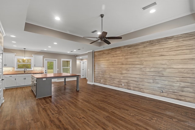 kitchen with wooden counters, hanging light fixtures, white cabinets, a kitchen island, and dark hardwood / wood-style flooring