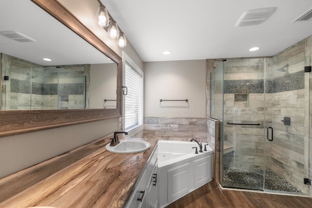 bathroom with tile walls, vanity, wood-type flooring, and plus walk in shower