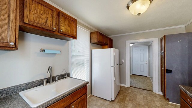 431 E Eufaula St, Ozark, AL 36360 - kitchen with freestanding refrigerator, a sink, light floors, dark countertops, and crown molding