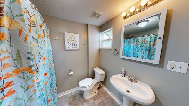 431 E Eufaula St, Ozark, AL 36360 - bathroom with baseboards, toilet, a sink, and a textured ceiling