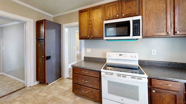 431 E Eufaula St, Ozark, AL 36360 - kitchen with white appliances, dark countertops, crown molding, brown cabinets, and baseboards
