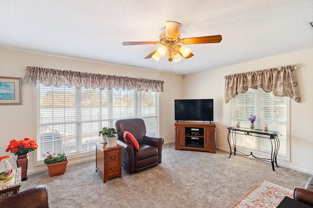 living area featuring baseboards, a ceiling fan, a textured ceiling, and light colored carpet