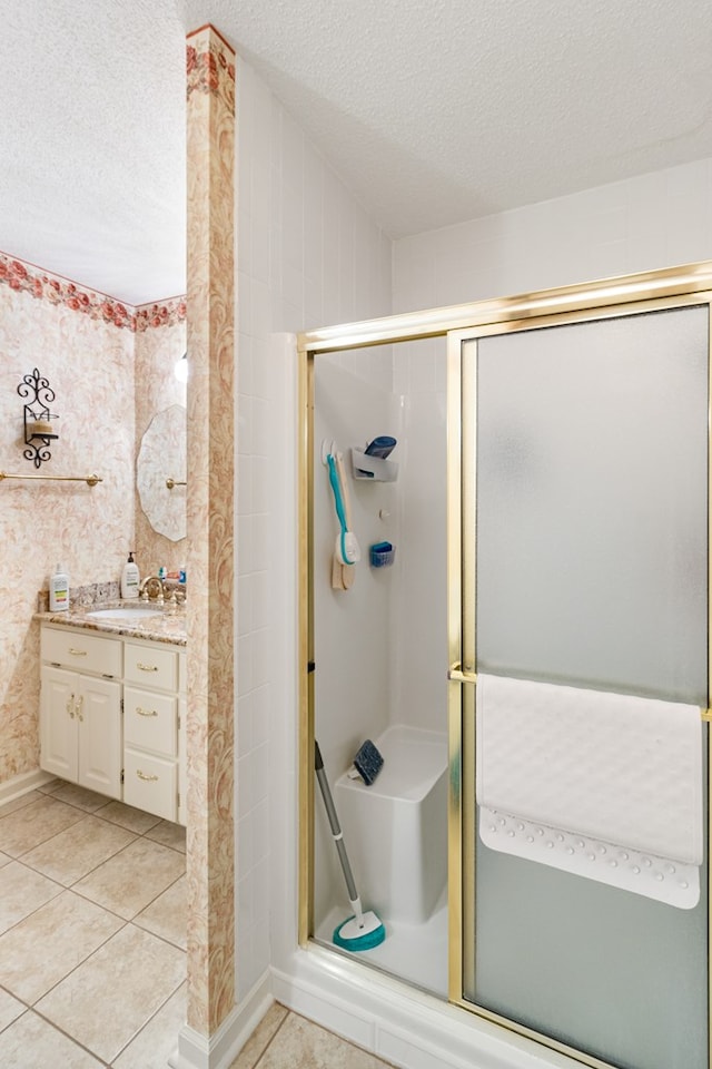 bathroom featuring wallpapered walls, tile patterned floors, a textured ceiling, vanity, and a shower stall