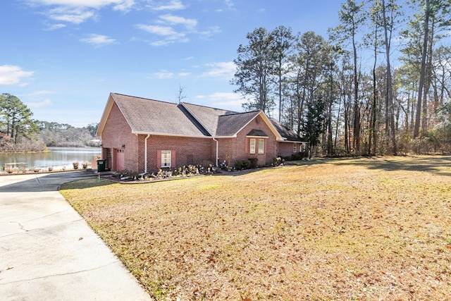 view of property exterior with brick siding, a yard, concrete driveway, a water view, and a garage