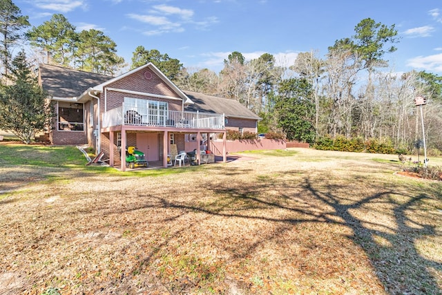 rear view of house with a yard, a wooden deck, and brick siding