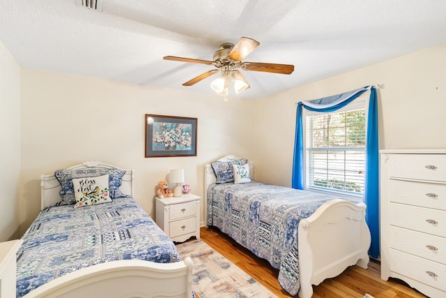 bedroom with visible vents, ceiling fan, a textured ceiling, and light wood finished floors