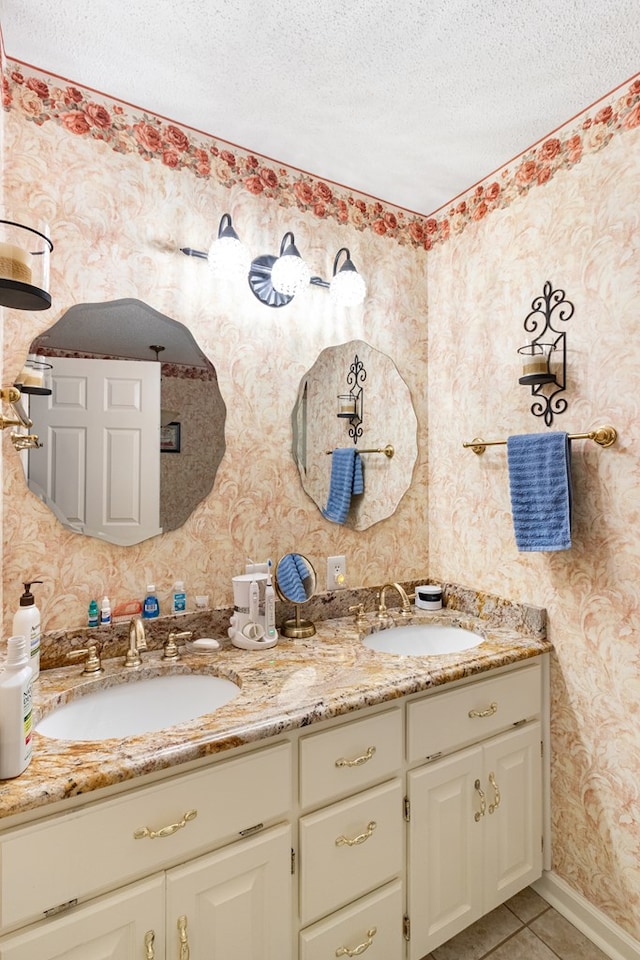 bathroom featuring a textured ceiling, tile patterned floors, a sink, and wallpapered walls