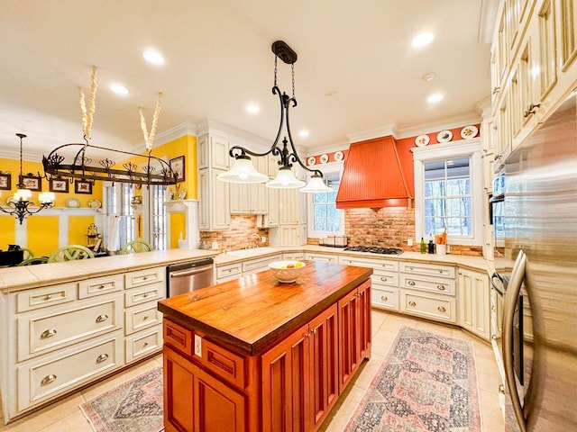 kitchen with kitchen peninsula, pendant lighting, decorative backsplash, custom range hood, and appliances with stainless steel finishes