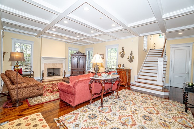 living room with a high end fireplace, coffered ceiling, ornamental molding, beam ceiling, and wood-type flooring