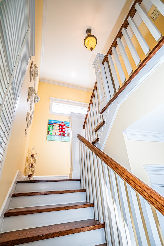 stairs with crown molding and a high ceiling