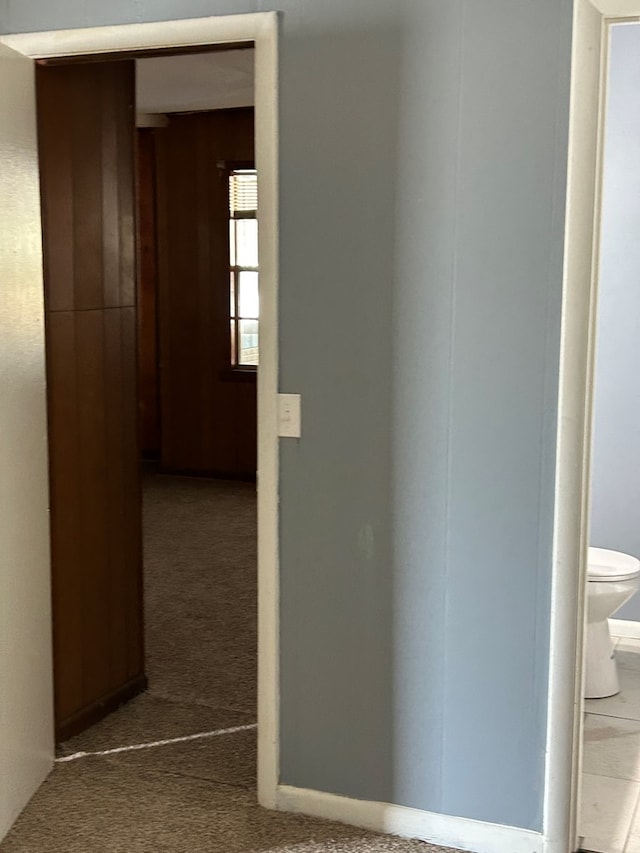 hallway featuring carpet flooring and wooden walls