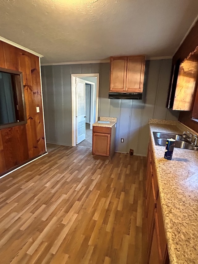 kitchen with hardwood / wood-style floors, a textured ceiling, crown molding, and sink