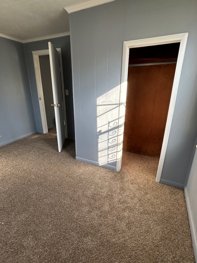 unfurnished bedroom with crown molding, a closet, and carpet