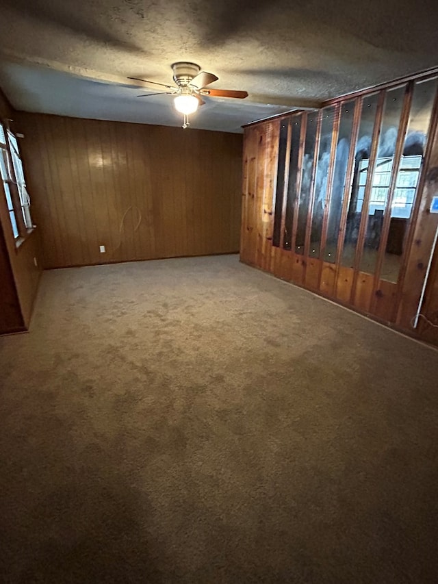 basement featuring a textured ceiling, carpet floors, and wooden walls