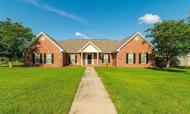 view of front facade with a front lawn, fence, and brick siding