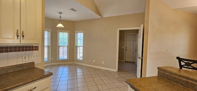 kitchen featuring lofted ceiling, backsplash, light tile patterned floors, and hanging light fixtures