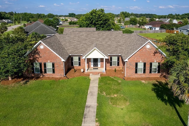 view of front of property featuring brick siding, roof with shingles, and a front yard