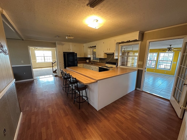 kitchen with white cabinets, dark hardwood / wood-style floors, kitchen peninsula, and a breakfast bar area