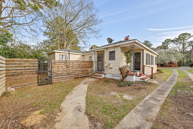 bungalow-style house featuring entry steps, fence, crawl space, a gate, and a chimney