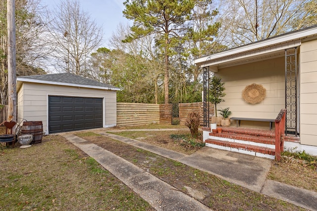 exterior space featuring a garage, fence, and an outbuilding