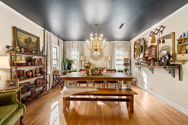 dining space with visible vents, baseboards, light wood-style flooring, an inviting chandelier, and a textured ceiling