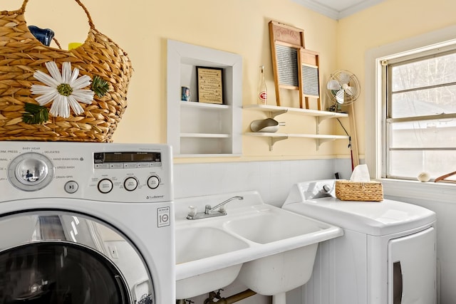 laundry room with washing machine and clothes dryer, ornamental molding, wainscoting, a sink, and laundry area