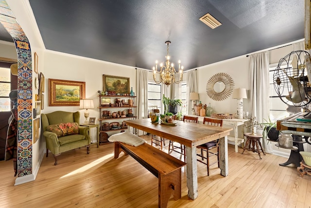 dining room featuring a chandelier, light wood-style flooring, plenty of natural light, and visible vents