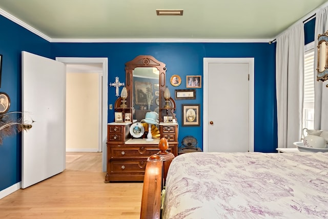 bedroom featuring visible vents, ornamental molding, and wood finished floors