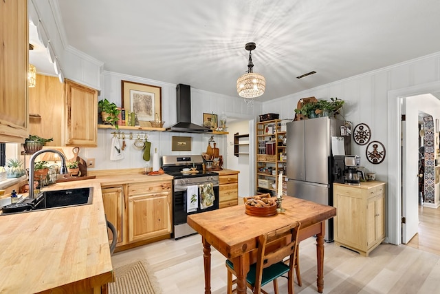 kitchen featuring stainless steel appliances, a sink, wood counters, and wall chimney range hood