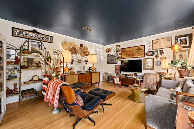 living area featuring visible vents and wood finished floors