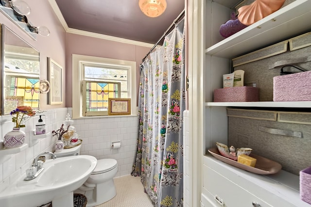 full bathroom featuring tile walls, toilet, a wainscoted wall, crown molding, and a sink