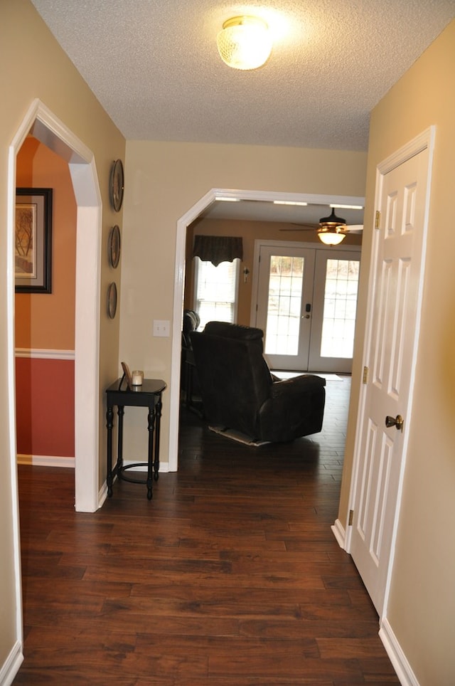 hall with dark hardwood / wood-style floors, a textured ceiling, and french doors