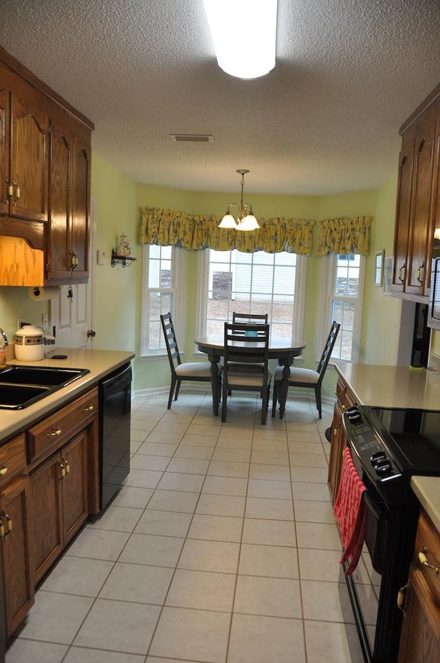 kitchen with light tile patterned floors, sink, hanging light fixtures, plenty of natural light, and black appliances