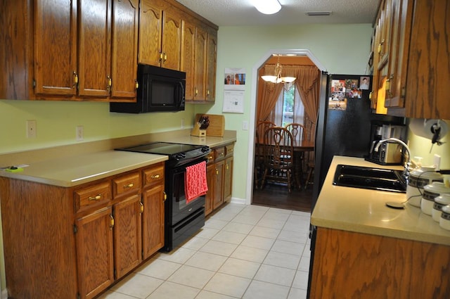 kitchen featuring light tile patterned flooring, sink, a chandelier, a textured ceiling, and black appliances