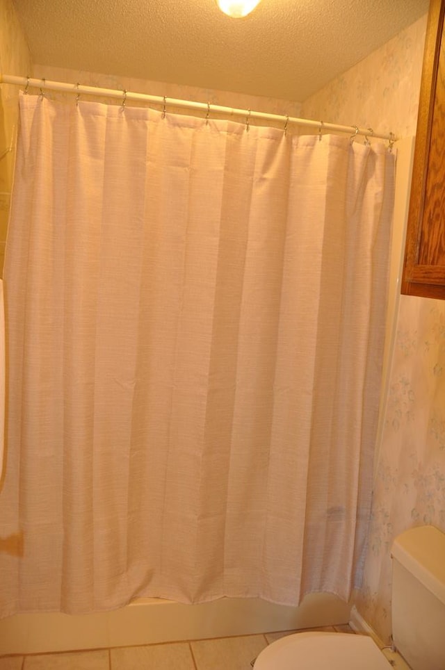 bathroom with tile patterned floors, a textured ceiling, and toilet