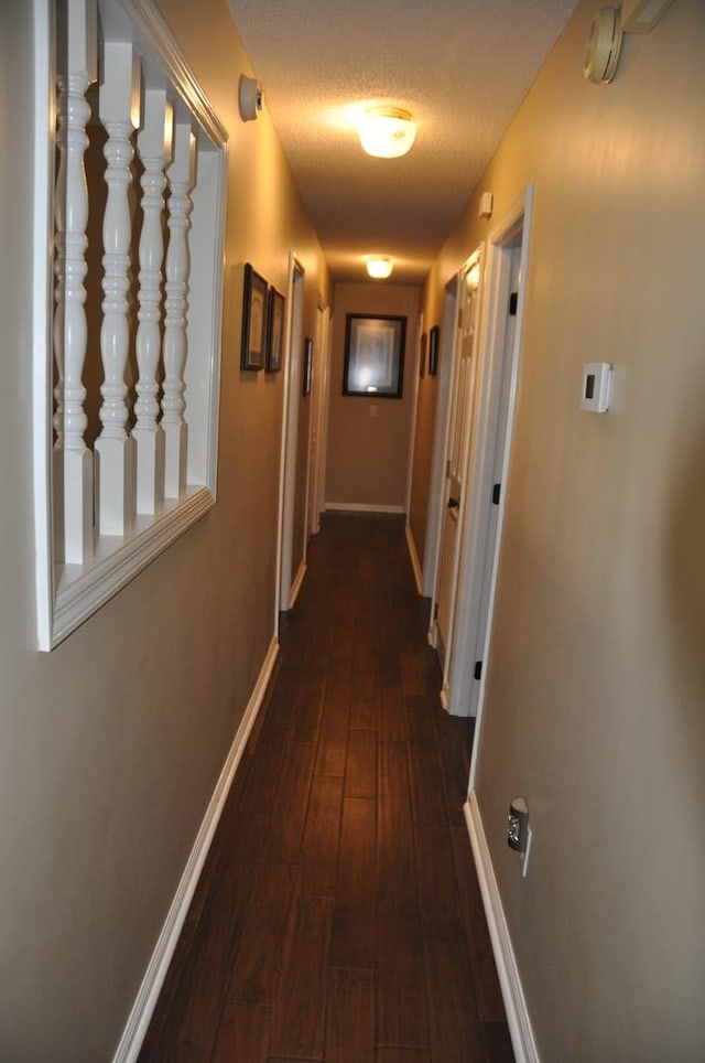 hallway with dark hardwood / wood-style flooring and a textured ceiling